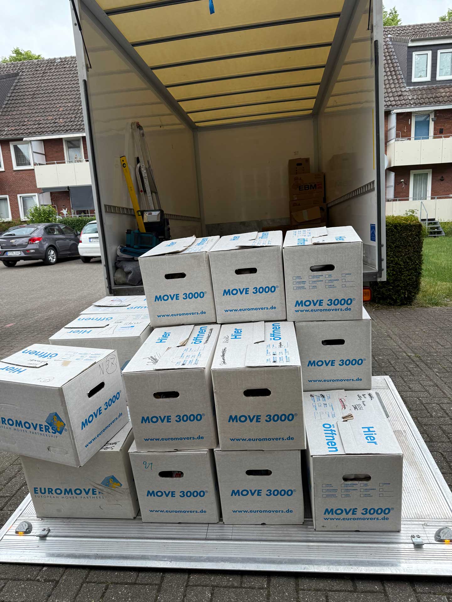Ein Umzugswagen mit angehobenem Dach, voll mit gestapelten Umzugskartons.